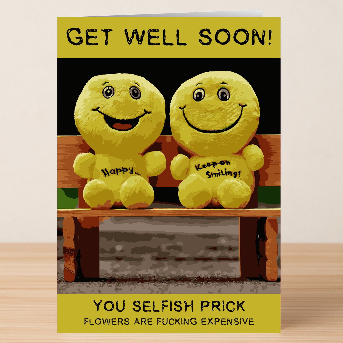 The Selfish Prick Insulting Get Well Soon Card by Twisted Gifts features two smiling yellow plush toys on a bench with the message: "Get well soon! You selfish prick. Flowers are fucking expensive." Perfect for friends with bold humor.