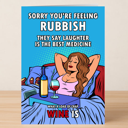 The Feeling Rubbish Funny Get Well Soon Card by Twisted Gifts features a woman in bed with wine, captioned: "Sorry you're feeling rubbish. They say laughter is the best medicine. What a load of crap wine is." Great for lifting spirits and making them smile!.