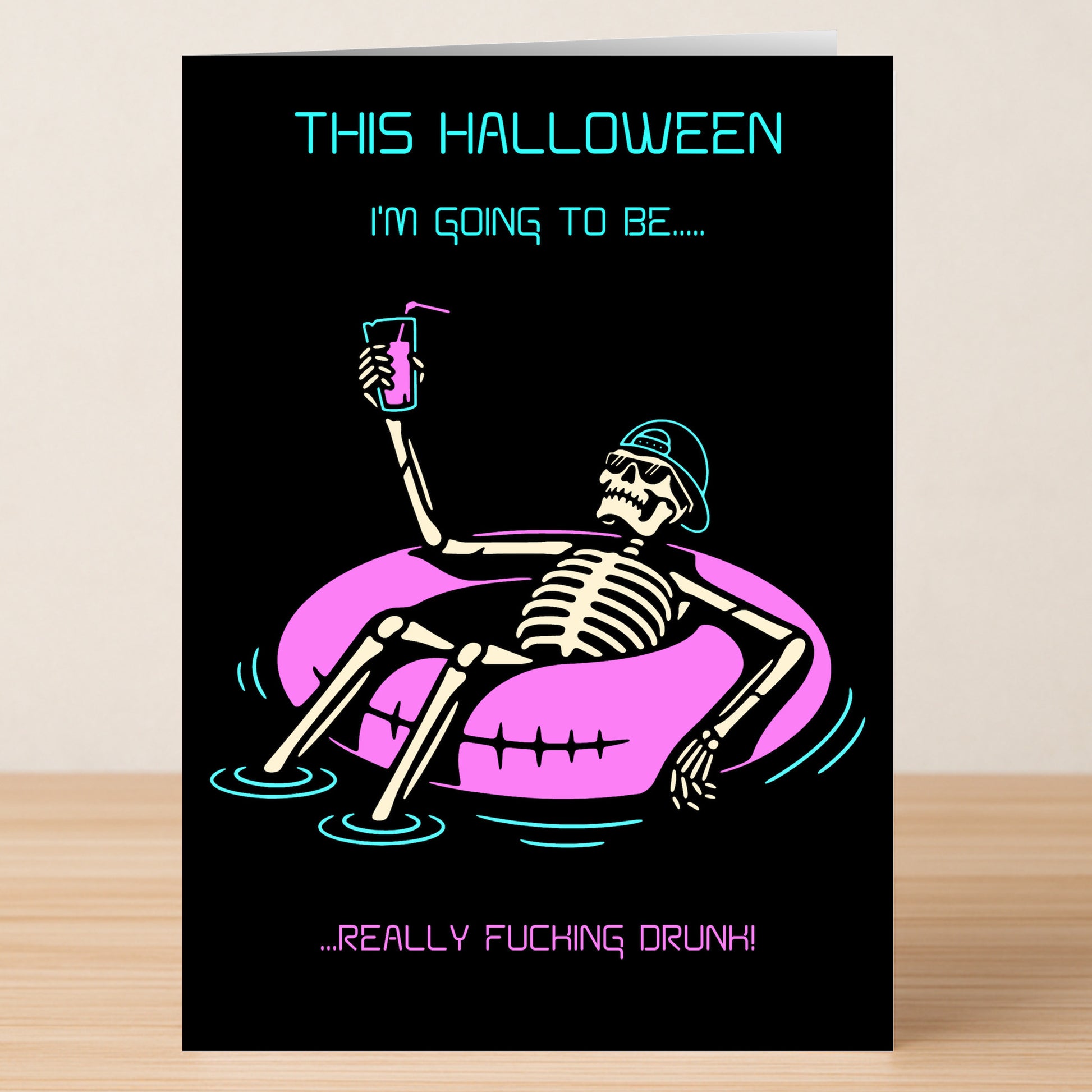The Really Drunk Funny Halloween Card by Twisted Gifts features a skeleton in sunglasses on a pink pool float with a drink. The card reads, "This Halloween I'm going to be... really fucking drunk!.