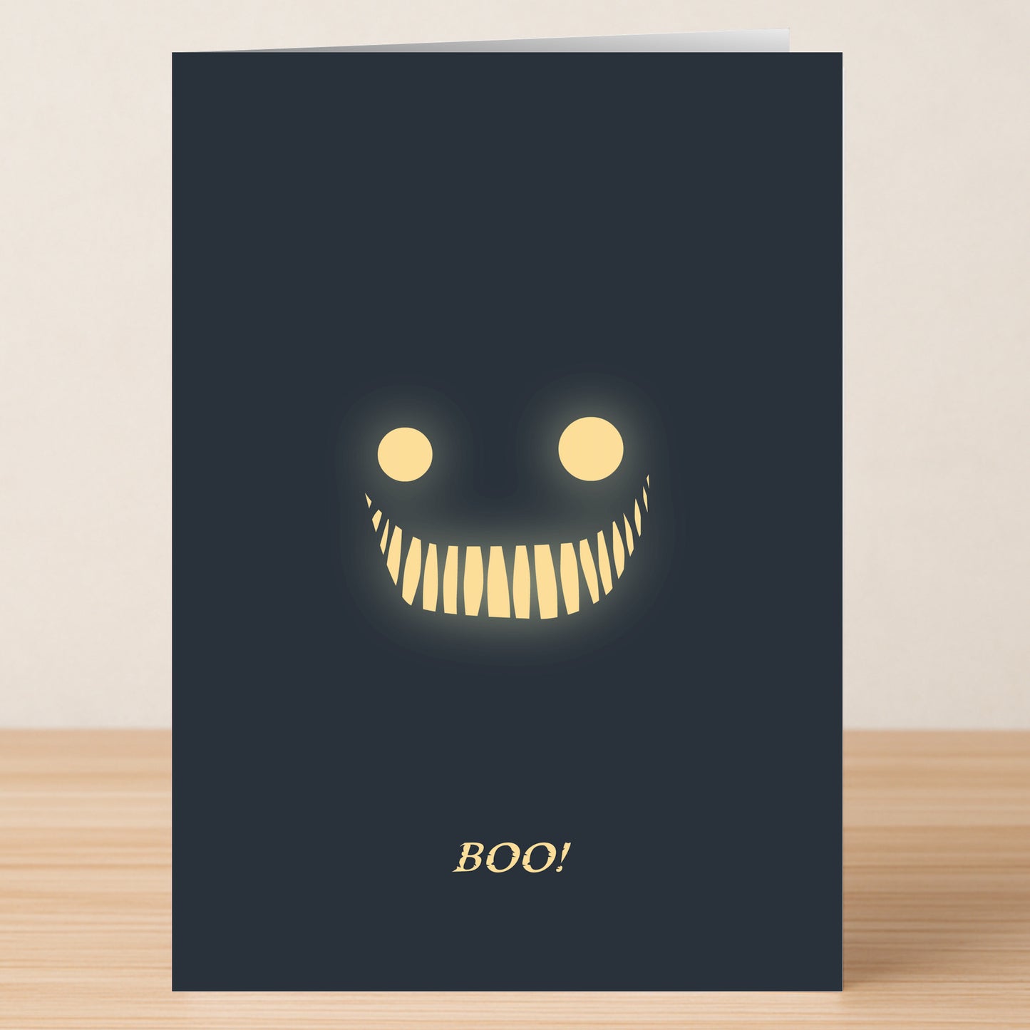 The Boo Funny Halloween Card by Twisted Gifts features a dark design with glowing yellow eyes, a wide toothy grin, and "BOO!" in gold—perfect for spooky laughs.