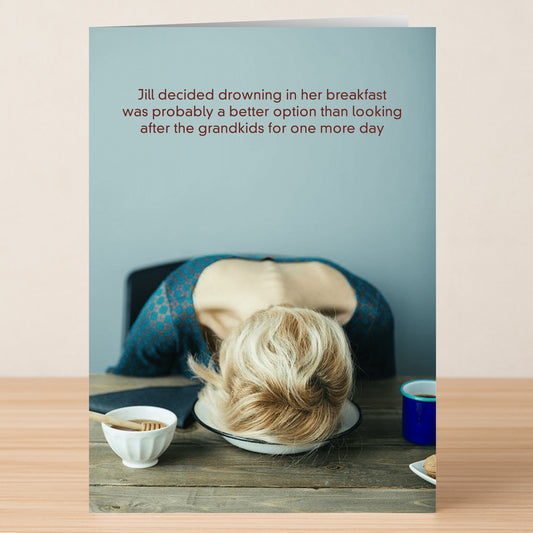 A woman slumps facedown in a bowl at the table, food and coffee nearby. The Twisted Gifts Grandkids Funny Mother's Day Card humorously captures grandma's exhaustion—perfect for gifting laughter this Mother's Day.