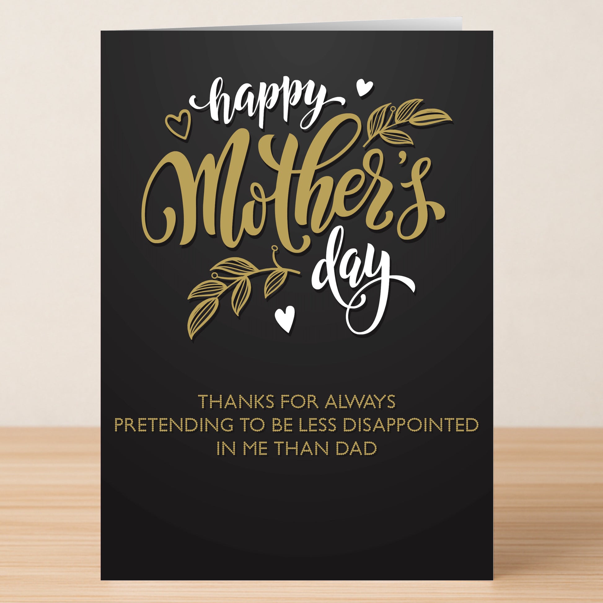 The Less Disappointed Funny Mother's Day Card by Twisted Gifts features gold and white text: "Happy Mother’s Day. Thanks for always pretending to be less disappointed in me than Dad.