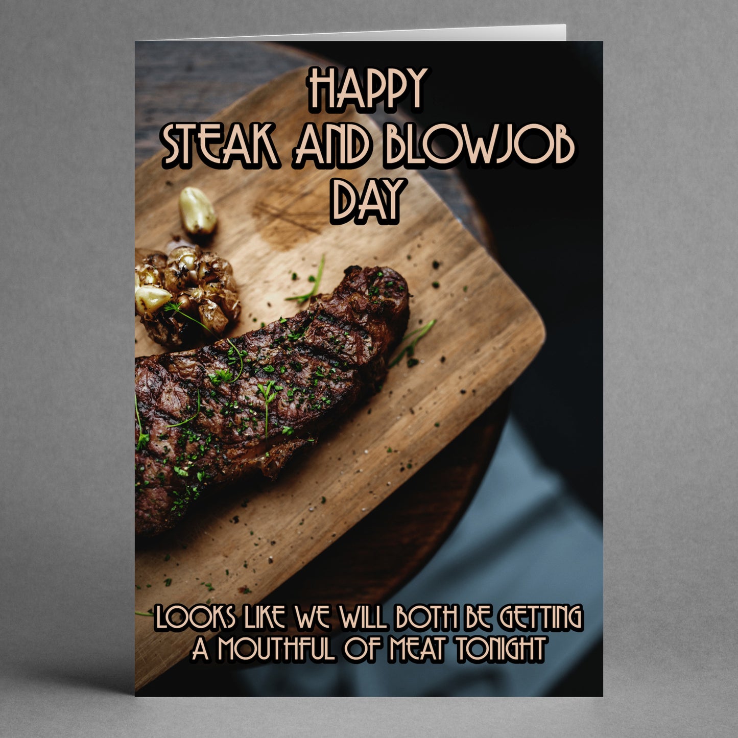 Introducing the "Mouthful Rude Steak And Blowjob Card" by Twisted Gifts. This cheeky greeting card features an image of a grilled steak on a wooden board, garnished with herbs and garlic, along with the playful message: "Happy Steak and Blowjob Day" and "Looks like we will both be getting a mouthful of meat tonight." Ideal for celebrating in a fun and irreverent way!