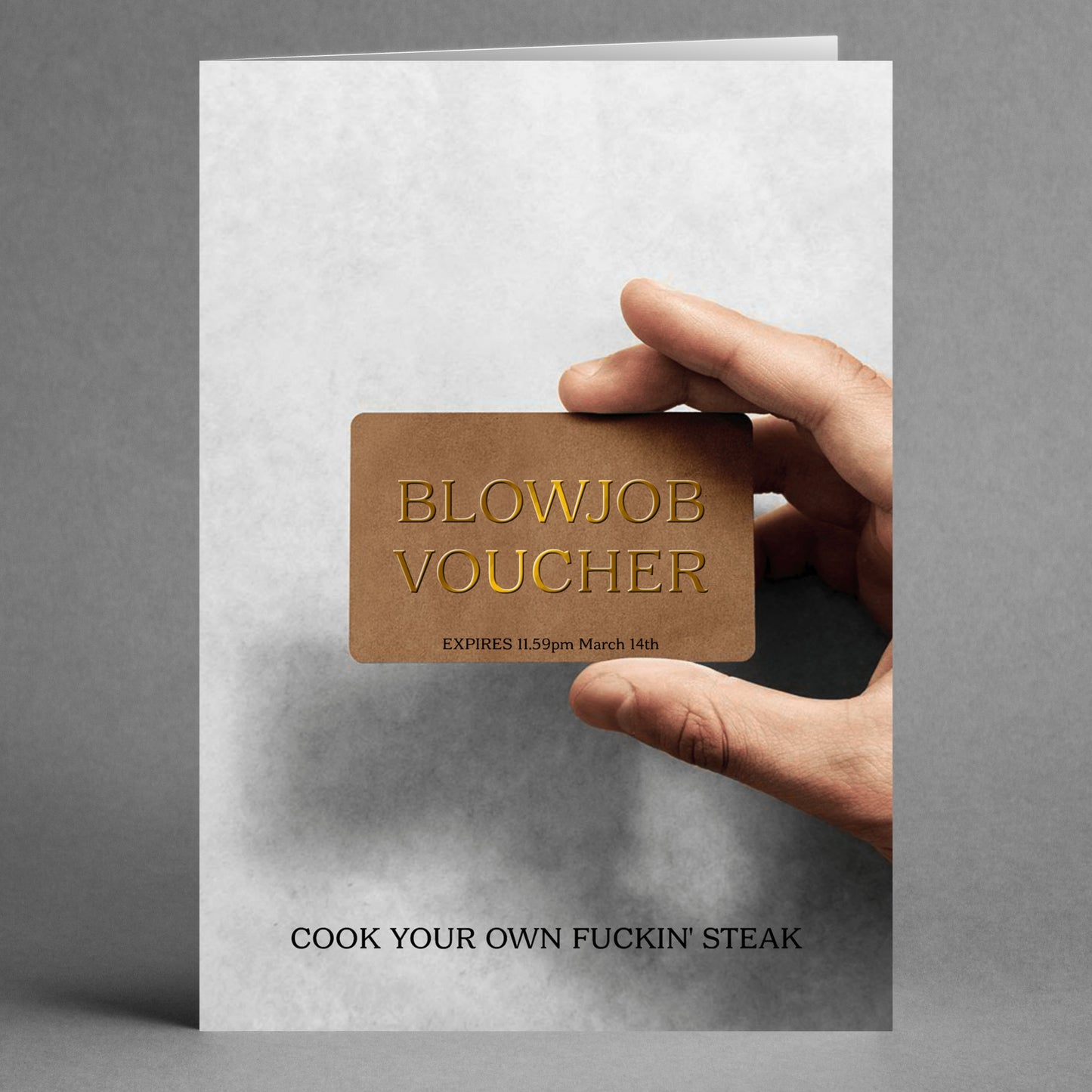 A hand holds a distinctive "Voucher Rude Steak And Blowjob Card" from Twisted Gifts, featuring an expiration date. Beneath, bold lettering cheekily states, "Cook your own fuckin' steak." It's the perfect cheeky twist on the ultimate Steak And Blowjob Card experience.