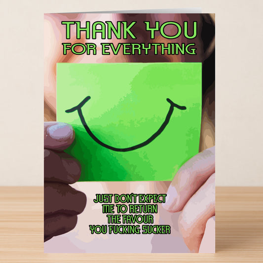 A person holds the Fucking Sucker Insulting Thank You Card by Twisted Gifts—a green card with a smiley face. Above: "Thank You For Everything." Below: "Just don't expect me to return the favour you fucking sucker." Dark humor perfection!.