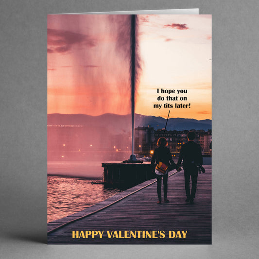 A couple holds hands, walking along a waterfront at sunset, as the "I Hope Rude Valentine's Card" from Twisted Gifts brings laughter to their stroll.