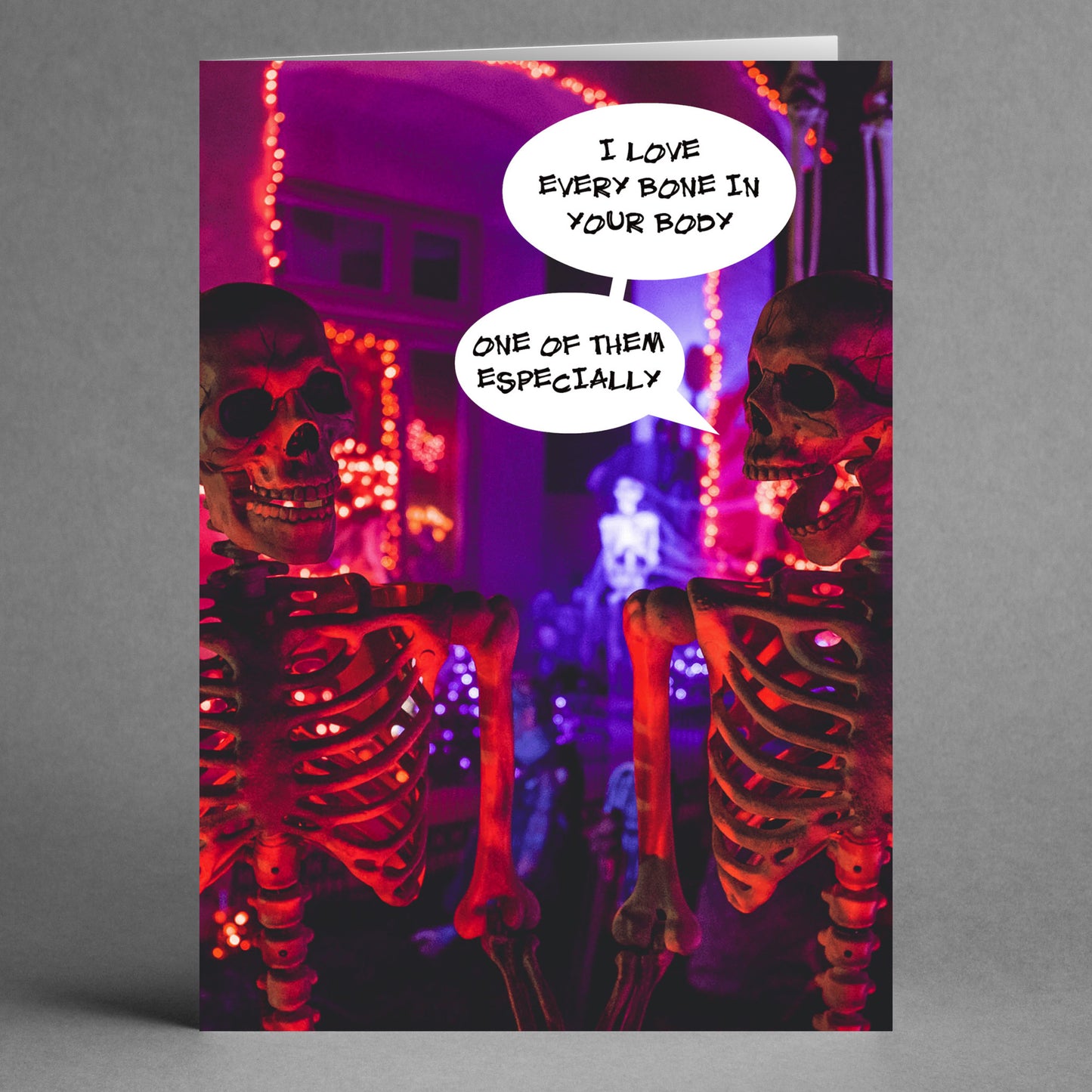 Two skeletons with speech bubbles feature on Twisted Gifts' Bones Funny Valentine's Card. One skeleton declares, "I love every bone in your body," while the other responds, "One of them especially." Glowing red and purple lights surround the scene, making it a perfect choice for a unique and humorous Valentine's card.