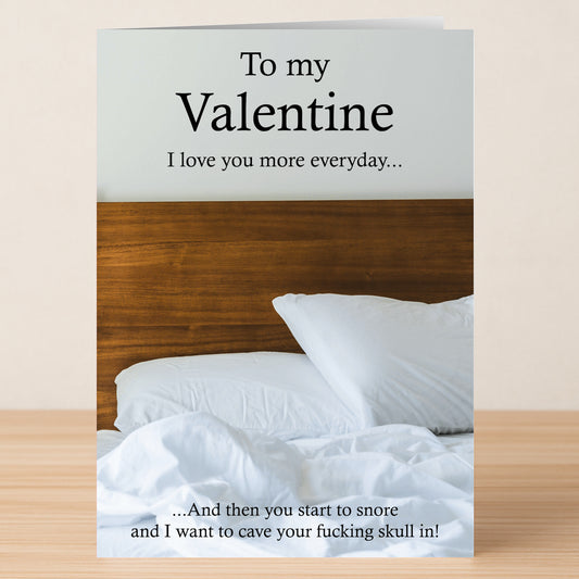 The Snore Funny Valentine's Card by Twisted Gifts features an unmade bed and the playful message: "To my Valentine. I love you more every day... And then you start to snore and I want to cave your skull in!" Perfect for quirky humor.