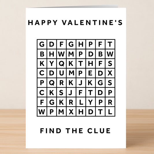 The Word Search Funny Valentine's Card by Twisted Gifts features "HAPPY VALENTINE'S" at the top and "FIND THE CLUE" at the bottom, displayed on a wooden surface.