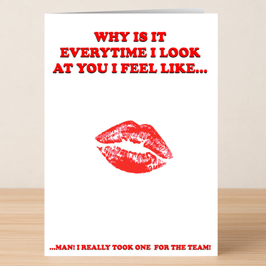 The Team Insulting Valentine's Card by Twisted Gifts puts a cheeky spin on romance with red text: "WHY IS IT EVERYTIME I LOOK AT YOU I FEEL LIKE..." above a lipstick kiss, and, "MAN! I REALLY TOOK ONE FOR THE TEAM!" at the bottom.