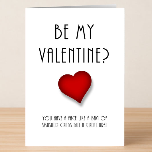 The Crabs Insulting Valentine's Card by Twisted Gifts features "Be My Valentine?" above a red heart and the cheeky line "You have a face like a bag of smashed crabs but a great arse," combining humor with affection.