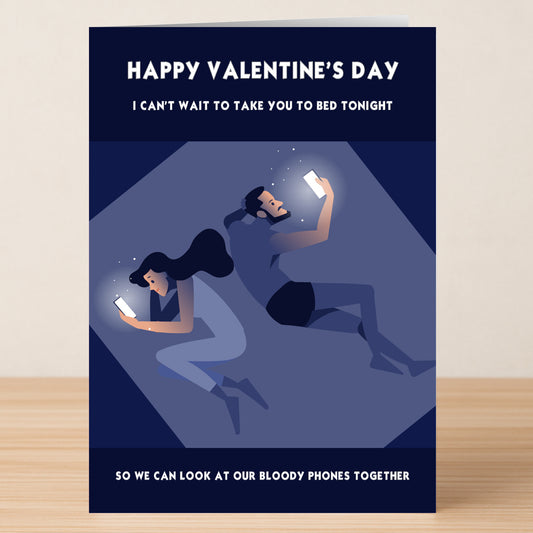 The "Bloody Phones Funny Valentine's Card" by Twisted Gifts pokes fun at modern love, showing a couple in bed back-to-back on their phones with witty text—perfect for anyone who'd rather scroll together than get romantic this Valentine’s Day.