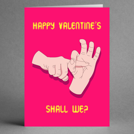 The Shall We Rude Valentine's Card by Twisted Gifts features a vibrant pink background with a playful message. It showcases two illustrated hands in an imaginative pose, with "HAPPY VALENTINE'S" at the top and the cheeky phrase "SHALL WE?" at the bottom.