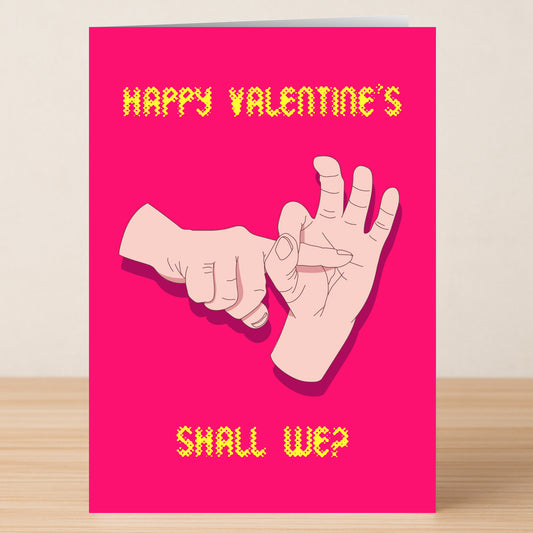 The Shall We Rude Valentine's Card by Twisted Gifts is a pink card with yellow text, "Happy Valentine's Shall We?", and a cheeky illustration of one hand making a hole and another inserting a finger.