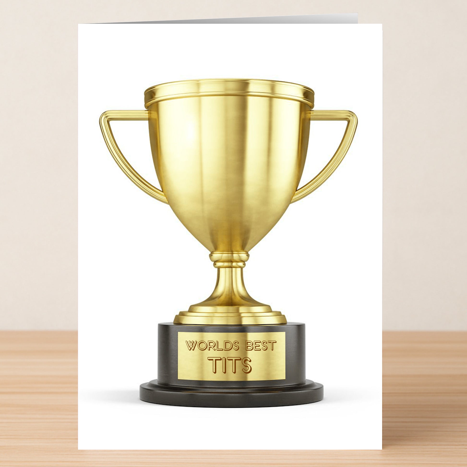 The Worlds Best Funny Valentine’s Card by Twisted Gifts features a gold trophy engraved with "WORLD'S BEST TITS," set against a plain background—ideal for sharing humor and love this Valentine's Day.