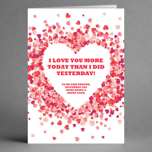 The Yesterday Funny Greeting Card from Twisted Gifts features a whimsical heart-shaped pattern with pink and red hearts. It includes the humorous message: "I love you more today than I did yesterday! To be fair though, yesterday you were being a right cock," promising to spark laughter and smiles.