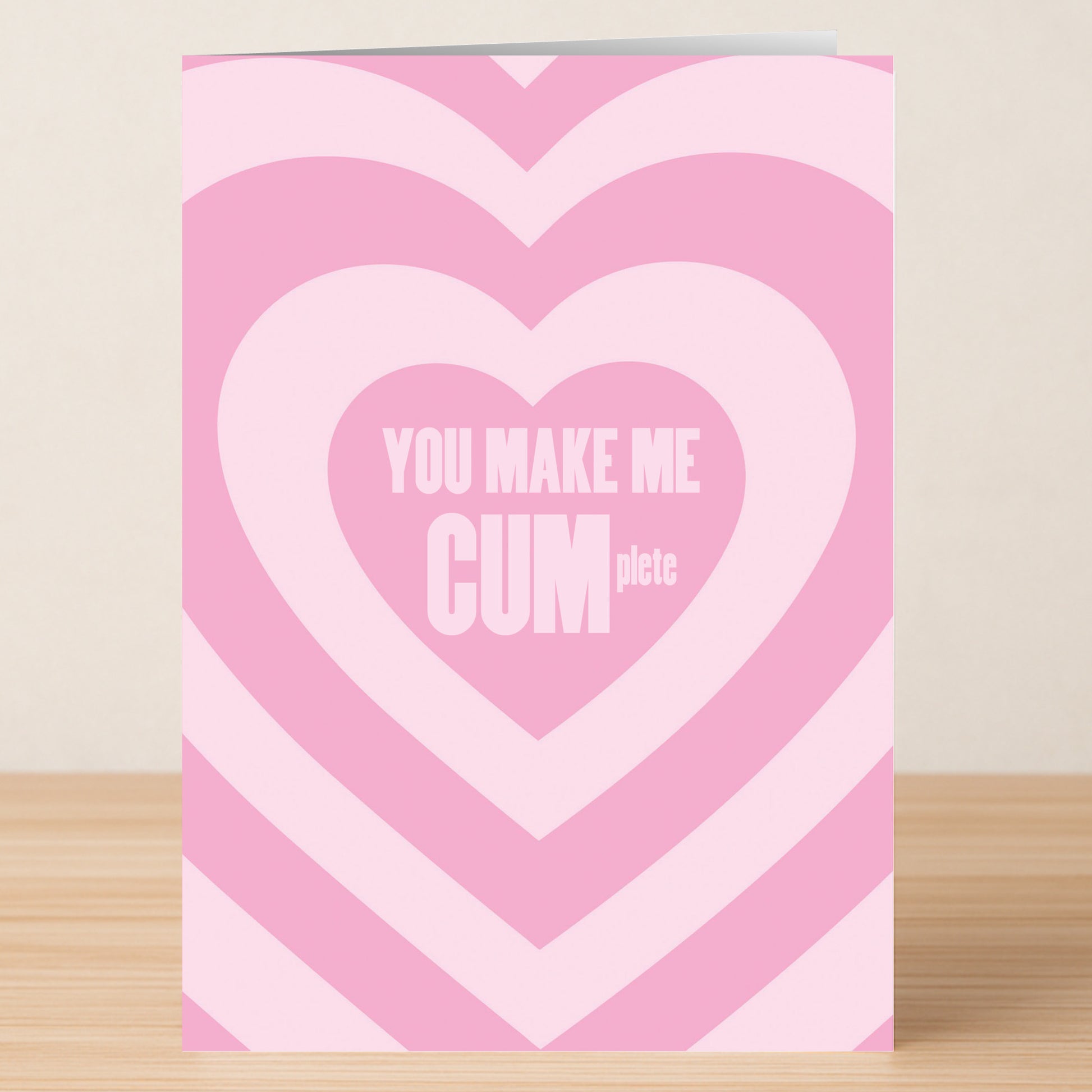 The Cumplete Rude Valentines Card by Twisted Gifts features concentric pink hearts and "YOU MAKE ME CUMplete" in bold white letters—ideal for anyone with a quirky sense of humor.