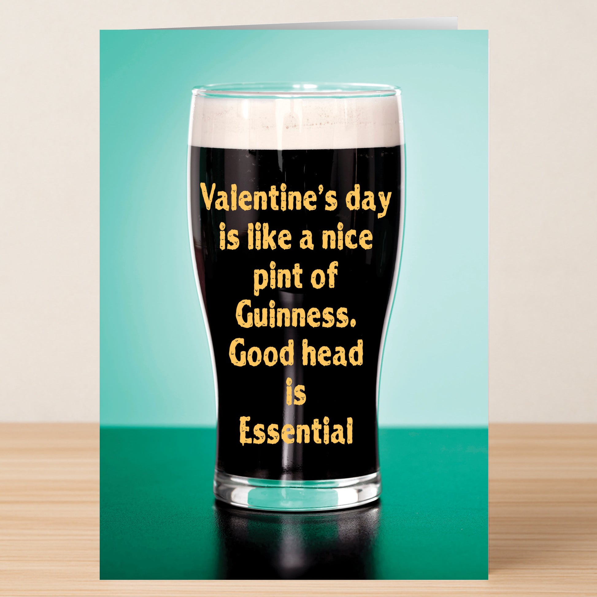 The Good Head Valentines Card by Twisted Gifts features a pint of Guinness with "Valentine’s day is like a nice pint of Guinness. Good head is Essential" printed on the glass, set on a teal background—a funny Valentine’s card.