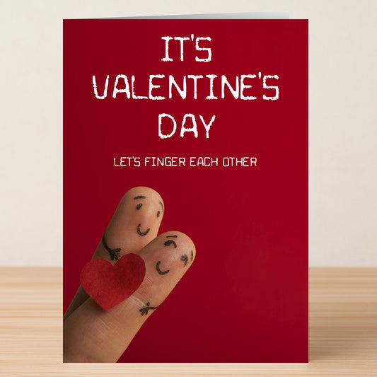 The Finger Rude Valentine's Card by Twisted Gifts features two fingers as smiling faces holding a red felt heart, with the cheeky message "IT'S VALENTINE'S DAY LET'S FINGER EACH OTHER." A fun and naughty choice for Valentine's Day!.