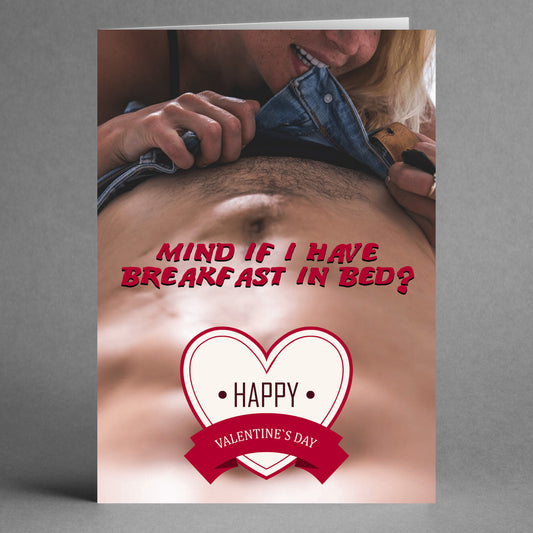 The "Breakfast In Bed Rude Valentine's Card" by Twisted Gifts showcases a cheeky illustration of a person's face near someone's bare stomach, accompanied by the playful text, "Mind if I have breakfast in bed?" A heart design enhances the charm of this delightfully humorous Valentine's card.