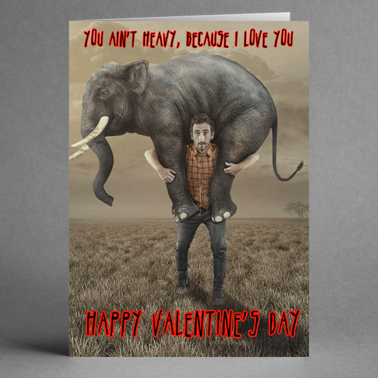 In a gray field, a man playfully carries a large elephant on his shoulders. The card reads, "You ain't heavy, because I love you. Happy Valentine's Day." As part of Twisted Gifts' collection, the Ain’t Heavy funny Valentine's Card is sure to delight with its unique and charming style.