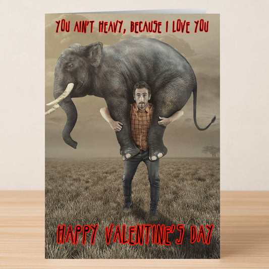 A man on a plain holds a large elephant on his shoulders, with text: “You ain’t heavy, because I love you.” The Ain’t Heavy funny Valentine’s Card from Twisted Gifts mixes humor and style for a unique greeting card.
