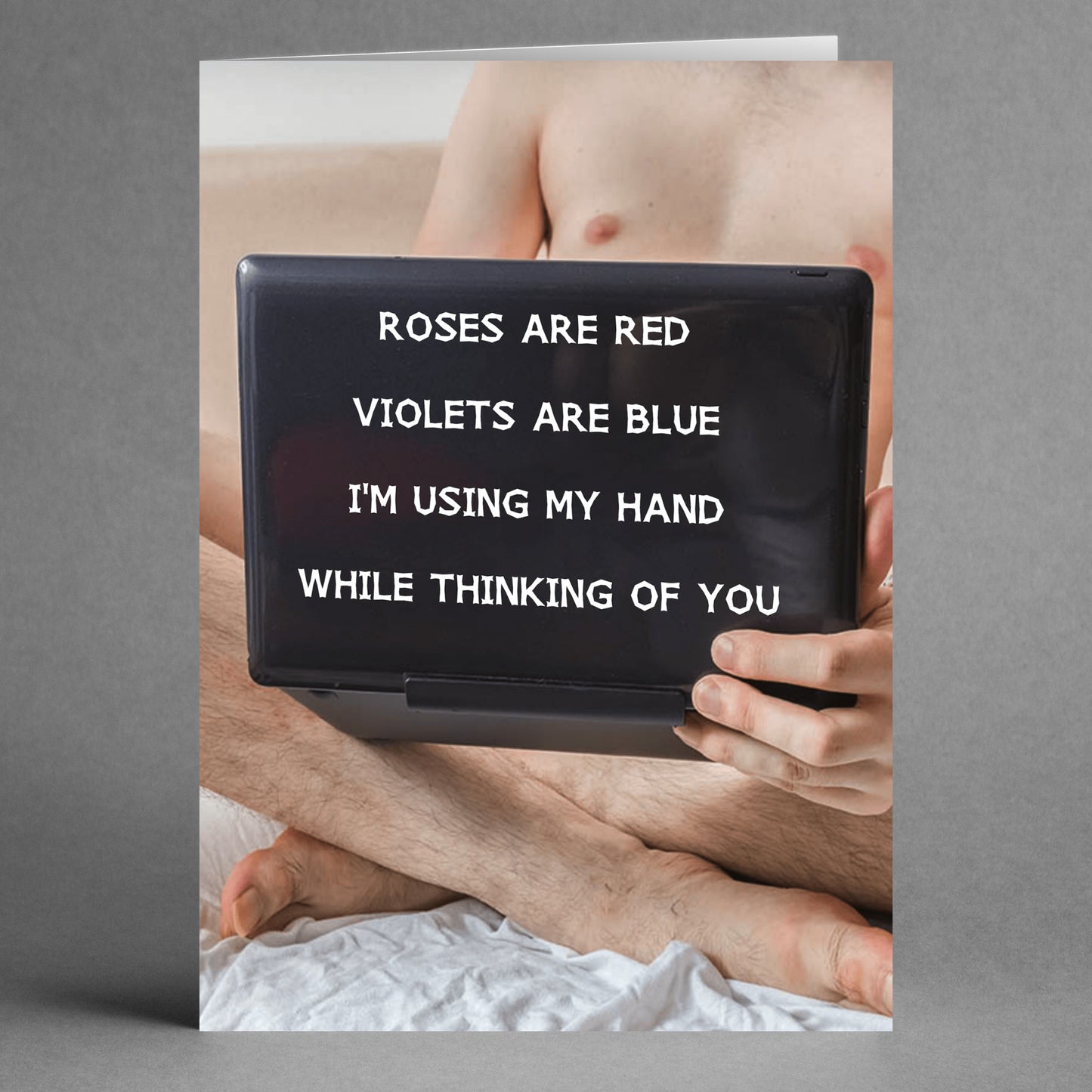 A person sits with a laptop on their lap, partially obscuring themselves, as they chuckle at a humorous message on the screen. It's a playful poem from the "Using My Hand Rude Valentine's Card" by Twisted Gifts, about using their hand while thinking of someone special.