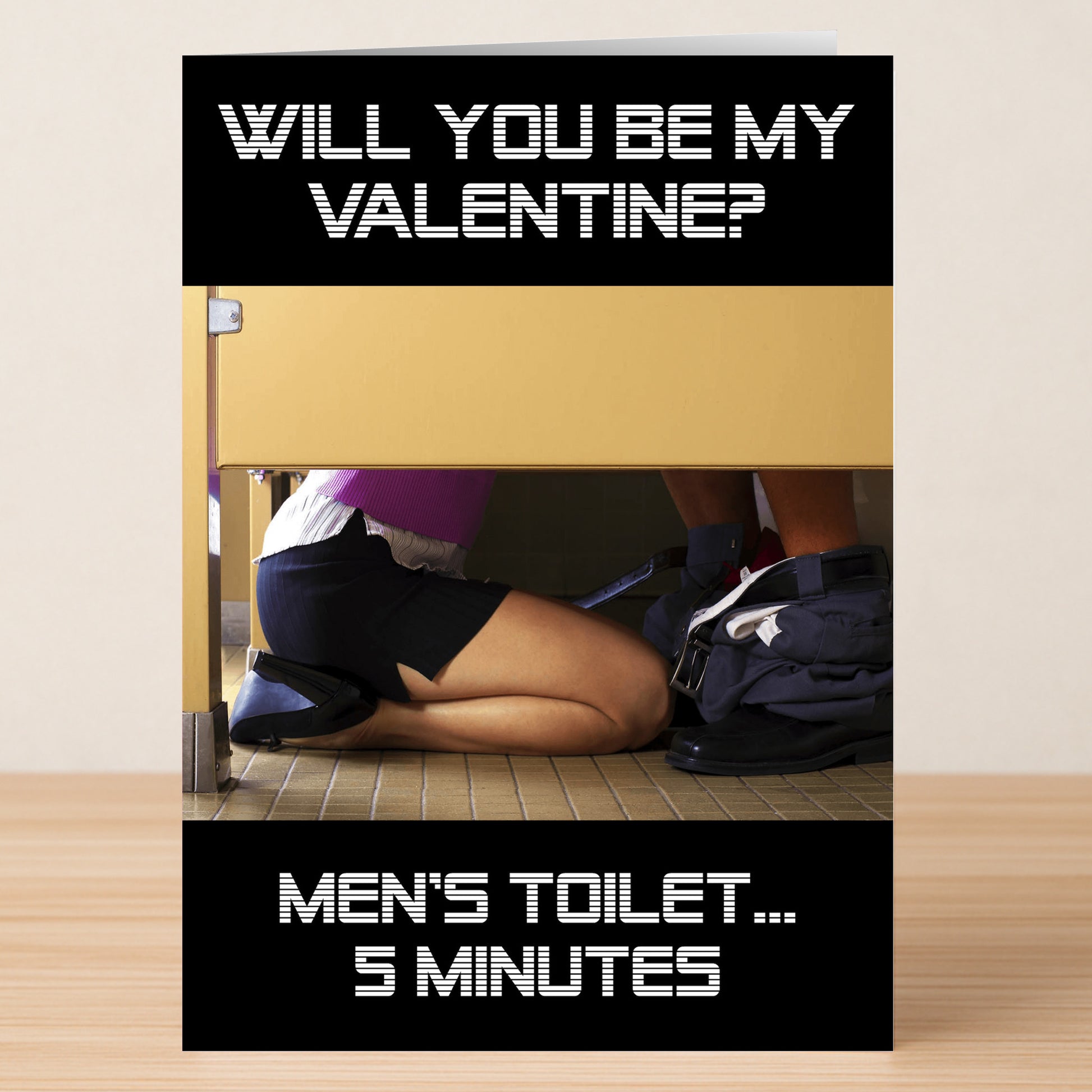 The 5 Minutes Funny Valentine’s Card by Twisted Gifts features “WILL YOU BE MY VALENTINE? MEN'S TOILET...5 MINUTES” with a person kneeling in a bathroom stall—an unforgettable, hilarious card for Valentine’s Day!.