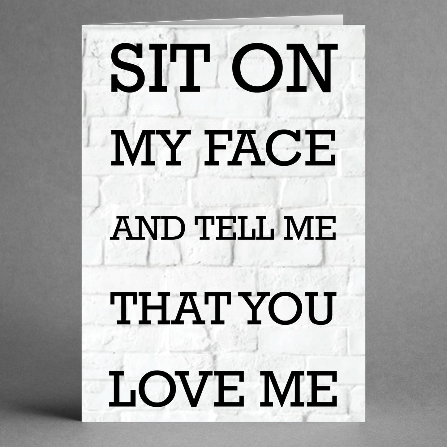 Check out the Sit On My Face Rude Valentine's Card by Twisted Gifts, featuring a white brick background with black text that humorously states, "SIT ON MY FACE AND TELL ME THAT YOU LOVE ME." Ideal for anyone in search of a cheeky and rude card for Valentine's Day.