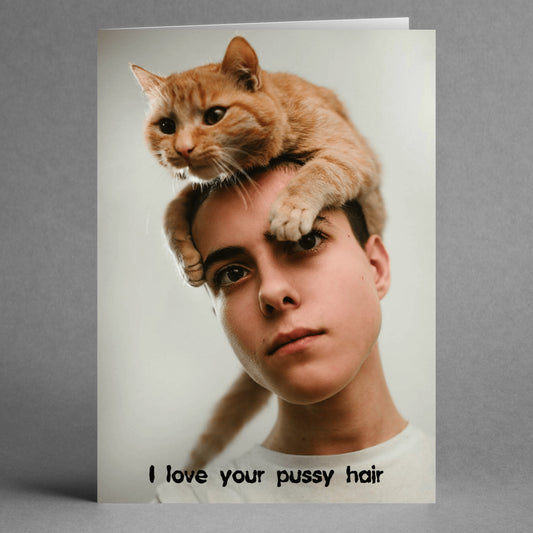 A person with a cat perched on their head, and text at the bottom saying, "I love your pussy hair." This is an ideal choice for a humorous Valentine's Day card from Twisted Gifts called the Pussy Hair Funny Valentine's Card.