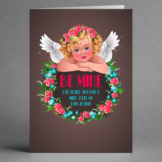 Twisted Gifts presents the Action Rude Valentine's Card, an imaginative greeting featuring a cherub with wings encircled by a floral wreath, complete with the playful text "Be Mine - I've heard you don't mind a bit of bim action." Perfect for those who enjoy an unconventional touch.