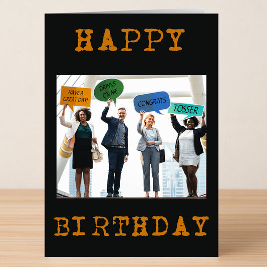 Four people in business attire hold colorful signs outdoors. The Great Day – Insulting Birthday Card by Twisted Gifts features "Happy Birthday" in orange on black, adding a touch of funny, insulting humor to this unique birthday card.