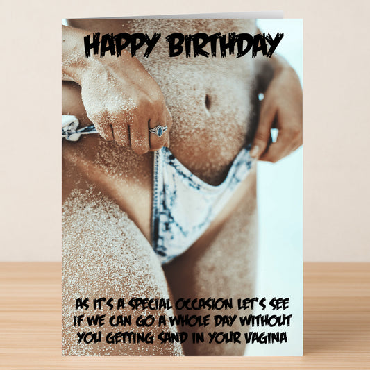 A close-up of a sandy person in swimwear holding their bikini bottom features on the "Sandy – Rude Birthday Card" by Twisted Gifts, paired with a humorous message about avoiding sand in intimate places.