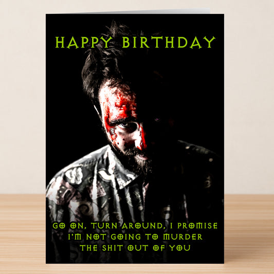 The Turn Around – Dark Humour Birthday Card by Twisted Gifts features "Happy Birthday," a person with fake blood on their face, and a darkly funny warning not to murder the recipient.