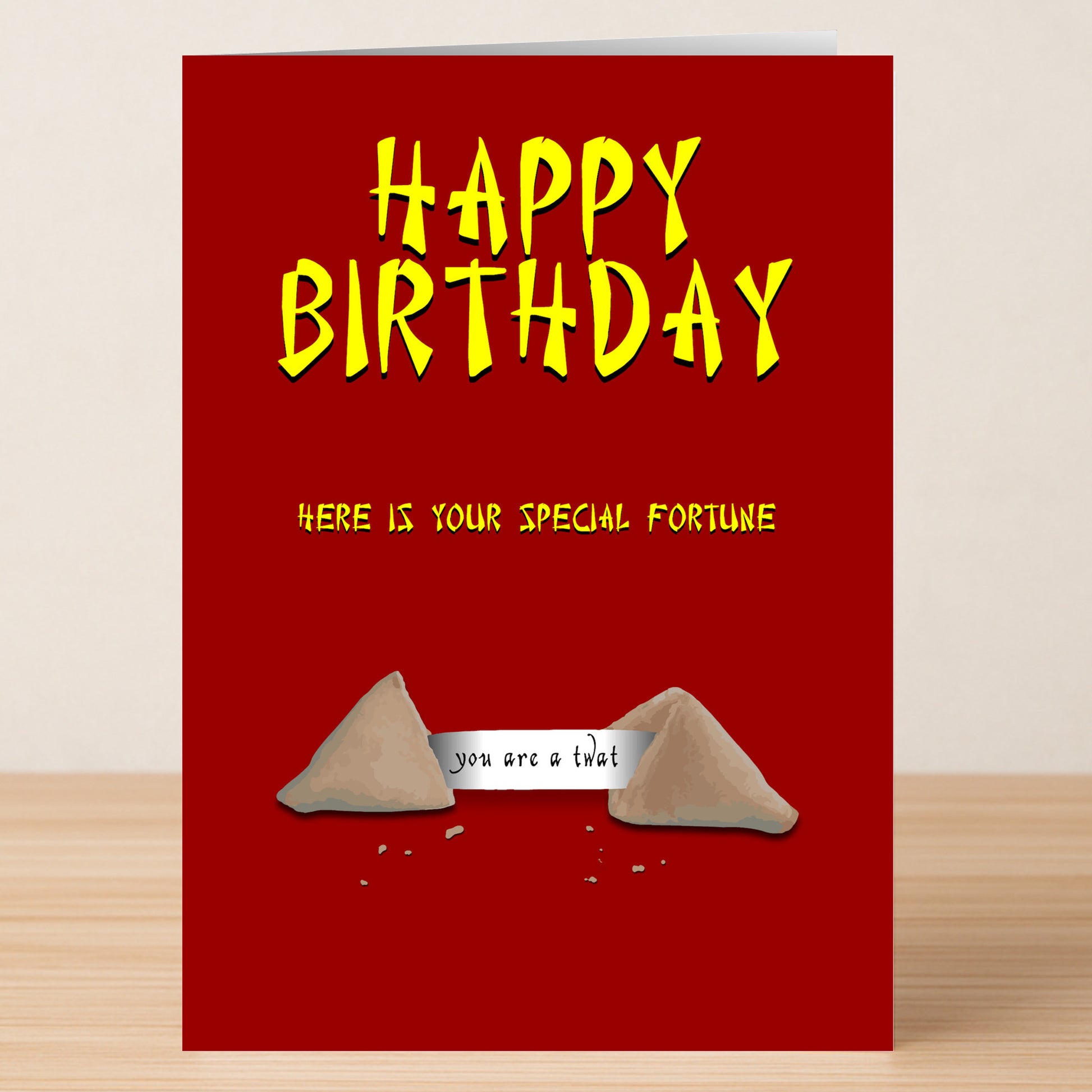 Twisted Gifts’ Fortune Cookies – Insulting Birthday Card features a red design with yellow text: “Happy Birthday” and “Here is your special fortune” above an opened cookie that reads, “you are a twat.”.