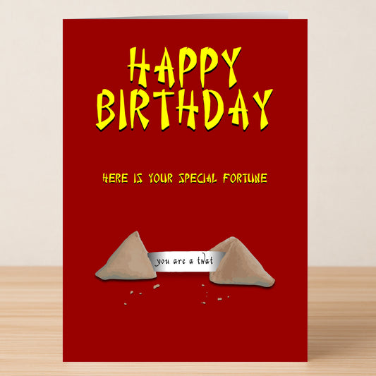 Twisted Gifts’ Fortune Cookies – Insulting Birthday Card features a red design with yellow text: “Happy Birthday” and “Here is your special fortune” above an opened cookie that reads, “you are a twat.”.