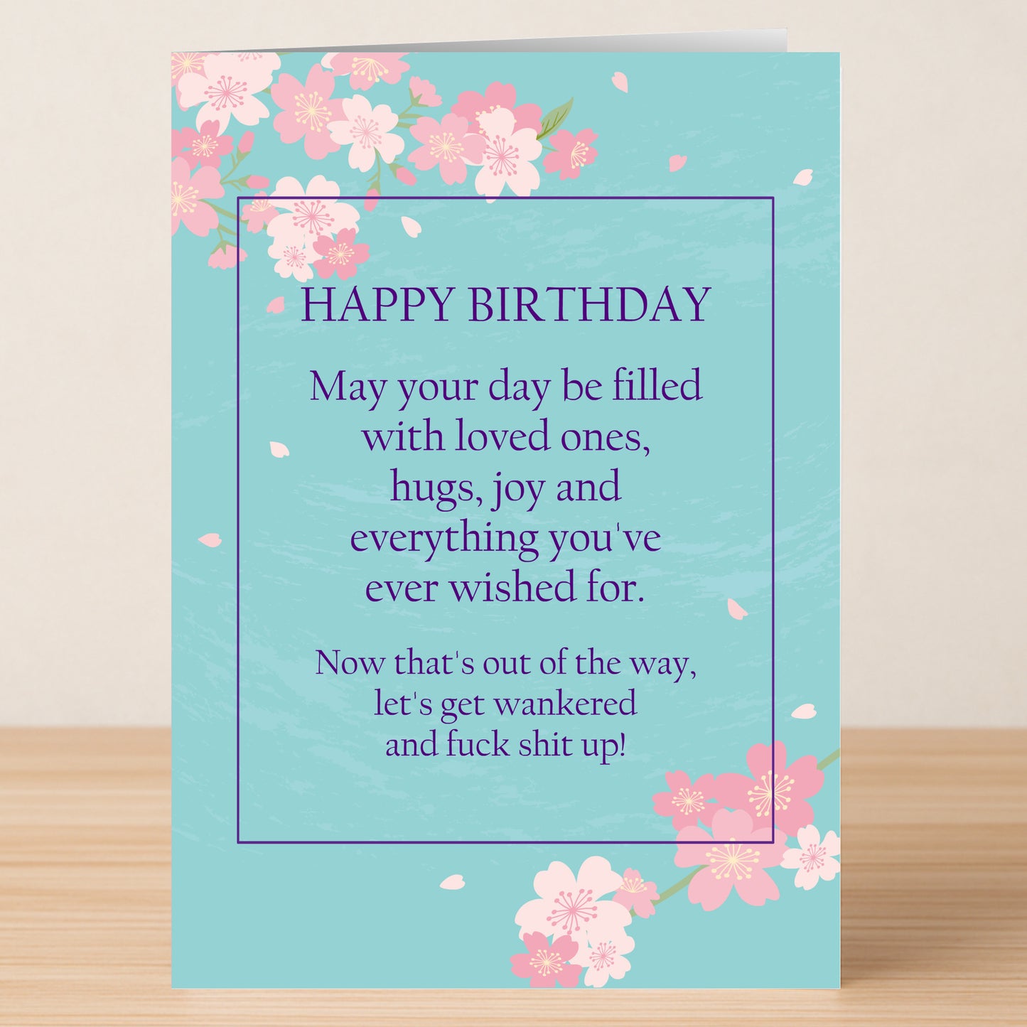 The Hugs And Joy – Funny Birthday Card by Twisted Gifts features pink cherry blossoms on a blue background, with a heartfelt message inside alongside a wickedly funny birthday greeting about celebrating in style.