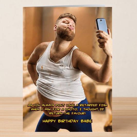 A bearded man in a ripped white tank and blue pants pouts for a selfie indoors on the Fish – Funny Birthday Card by Twisted Gifts, featuring "Happy birthday babe" with a humorous message above.