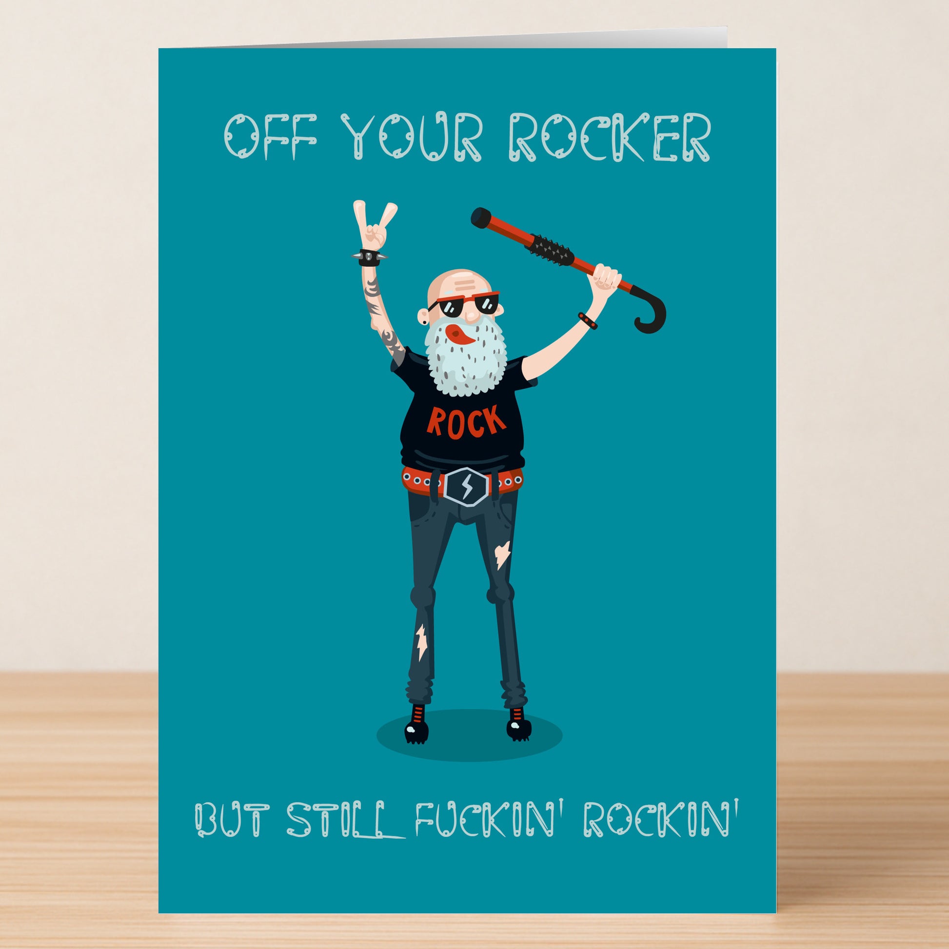 The Rocker – Funny Birthday Card by Twisted Gifts features an older man in rock attire with a cane, making a hand gesture and the text "OFF YOUR ROCKER BUT STILL FUCKIN' ROCKIN'" on teal—a hilarious choice for bold-humored birthdays.