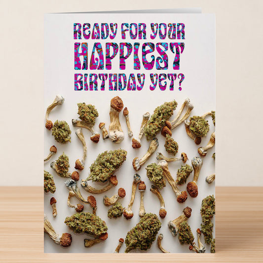 The Happiest Yet – Funny Birthday Card by Twisted Gifts features cannabis buds and dried mushrooms under vibrant, patterned text that reads, "Ready for your happiest birthday yet?.