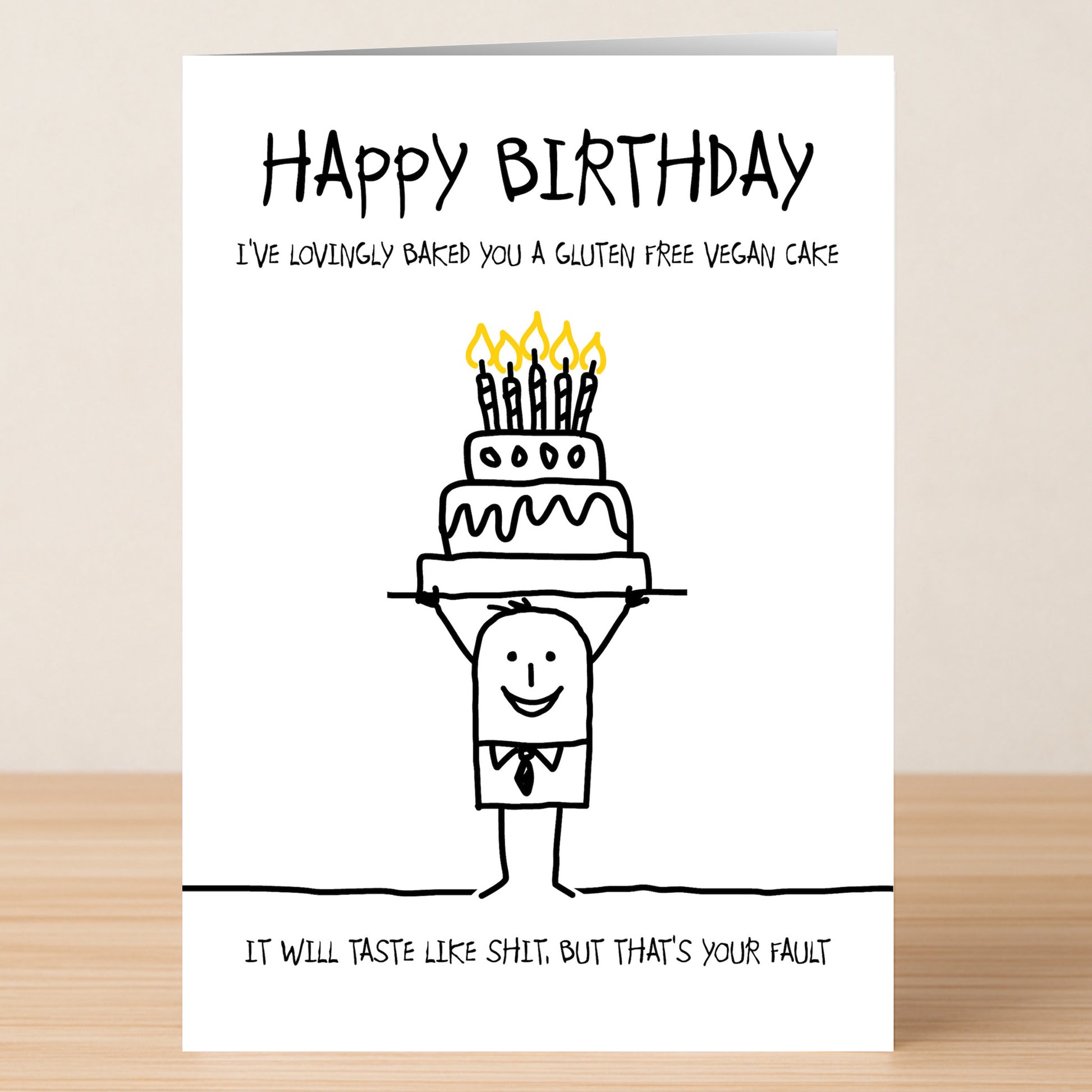 The GFV Cake – Insulting Birthday Card by Twisted Gifts features a stick figure holding a birthday cake with candles and reads: "Happy Birthday. I’ve lovingly baked you a gluten free vegan cake. It will taste like shit. But that’s your fault.