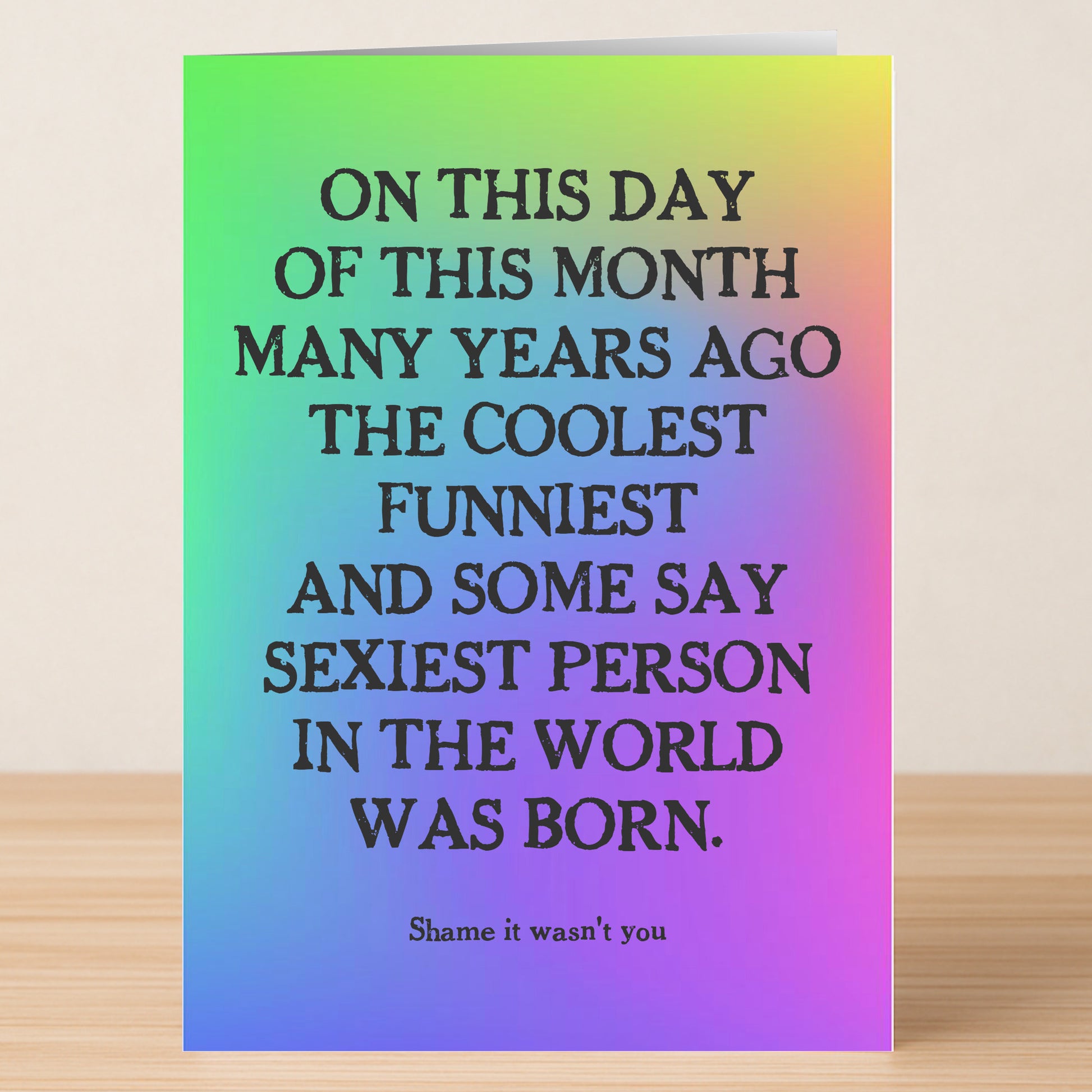 The "On This Day – Insulting Birthday Card" by Twisted Gifts features a rainbow gradient and bold black text that humorously states the coolest, funniest, sexiest person was born today—shame it wasn’t you! A hilariously cheeky birthday card.