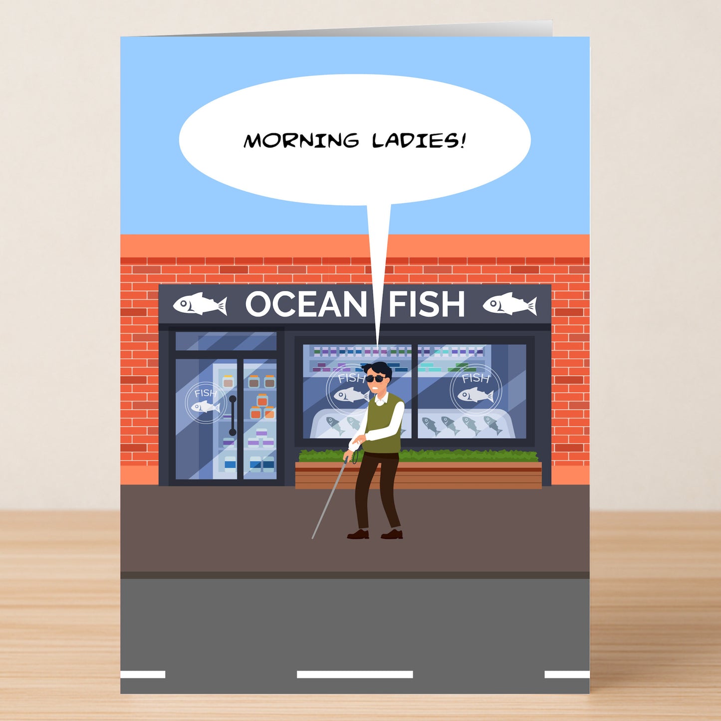 The Twisted Gifts “Morning Ladies” funny birthday card features a blind man with a white cane greeting fish in the "Ocean Fish" shop window, creating a playful fish market joke.