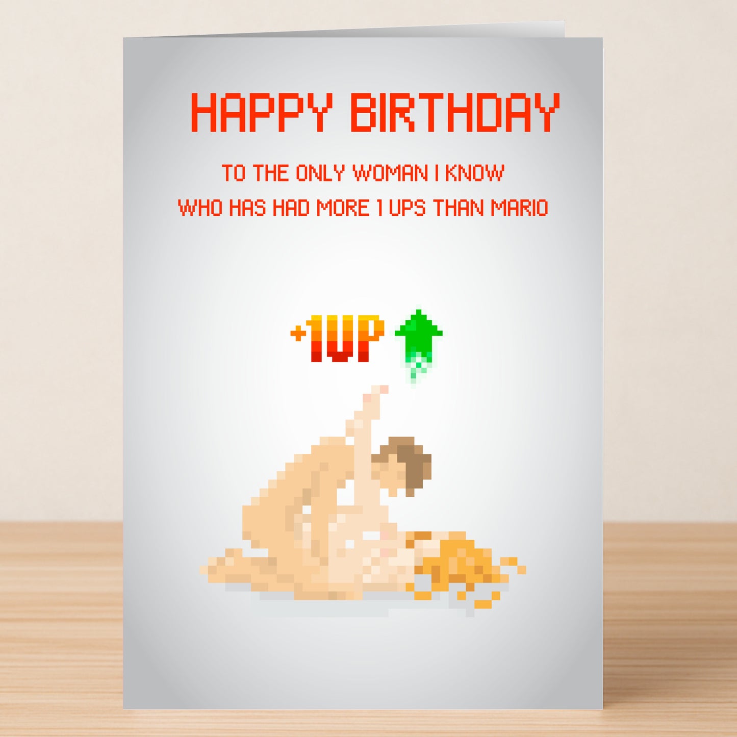 The 1 Up Woman Rude Birthday Card by Twisted Gifts features pixel art of two nude figures in a cheeky pose with the message: "Happy Birthday to the only woman I know who has had more 1 ups than Mario. +1UP." Perfect for bold humor lovers!.