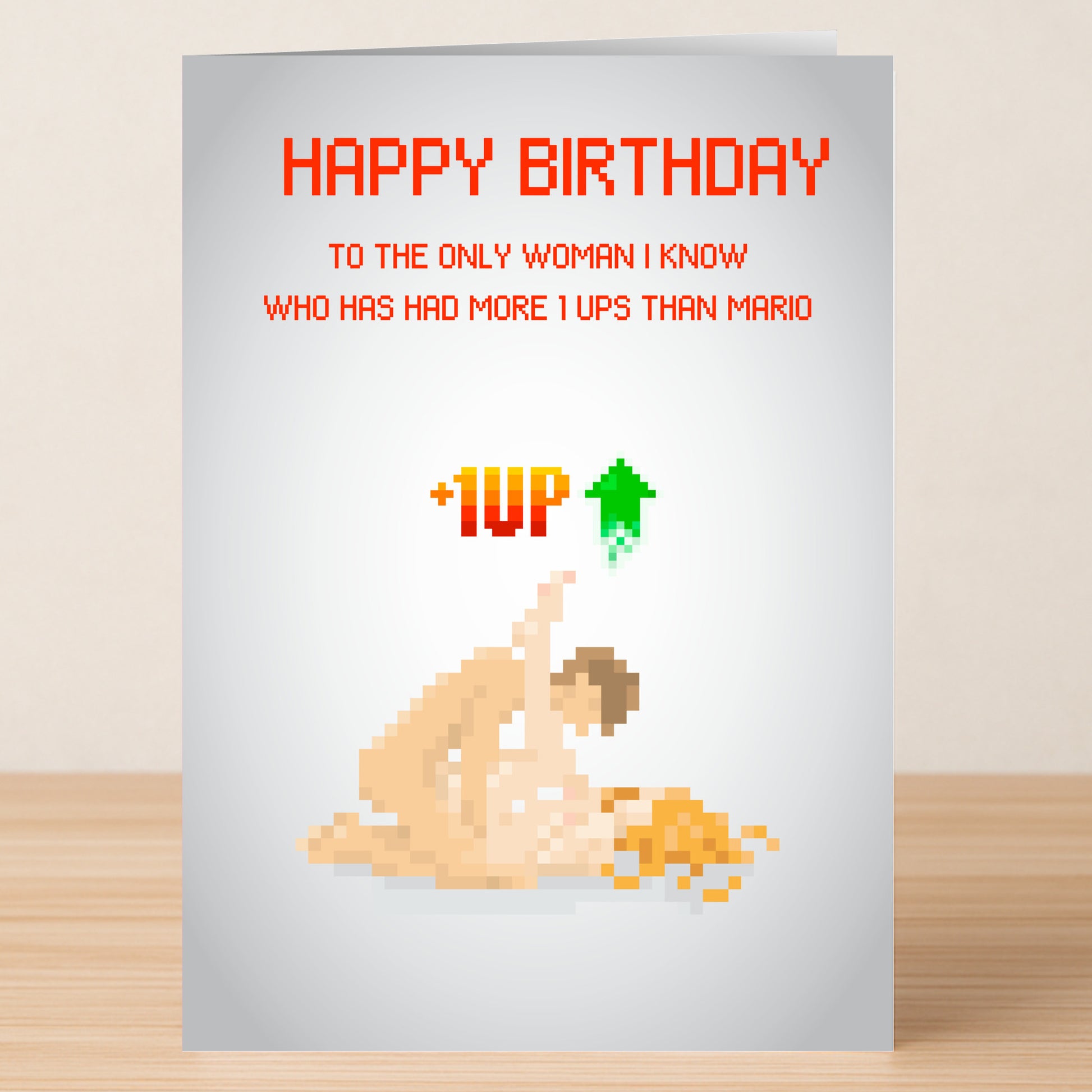 The 1 Up Woman Rude Birthday Card by Twisted Gifts features pixel art of two nude figures in a cheeky pose with the message: "Happy Birthday to the only woman I know who has had more 1 ups than Mario. +1UP." Perfect for bold humor lovers!.