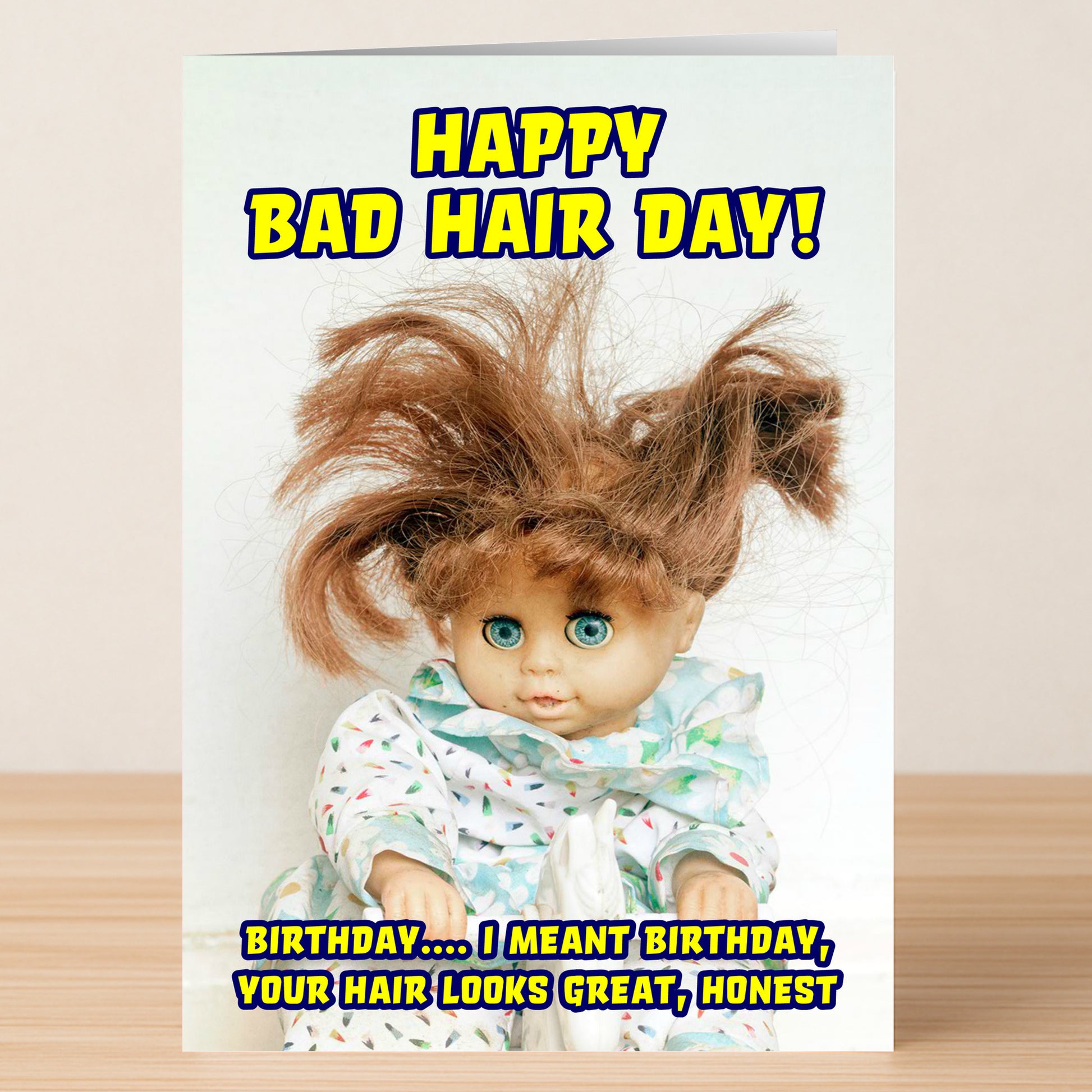 The Bad Hair Day Funny Birthday Card by Twisted Gifts features a doll with messy hair and wide eyes alongside the text: "Happy Bad Hair Day! Birthday... I meant Birthday, your hair looks great, honest." Perfect for sharing laughs.