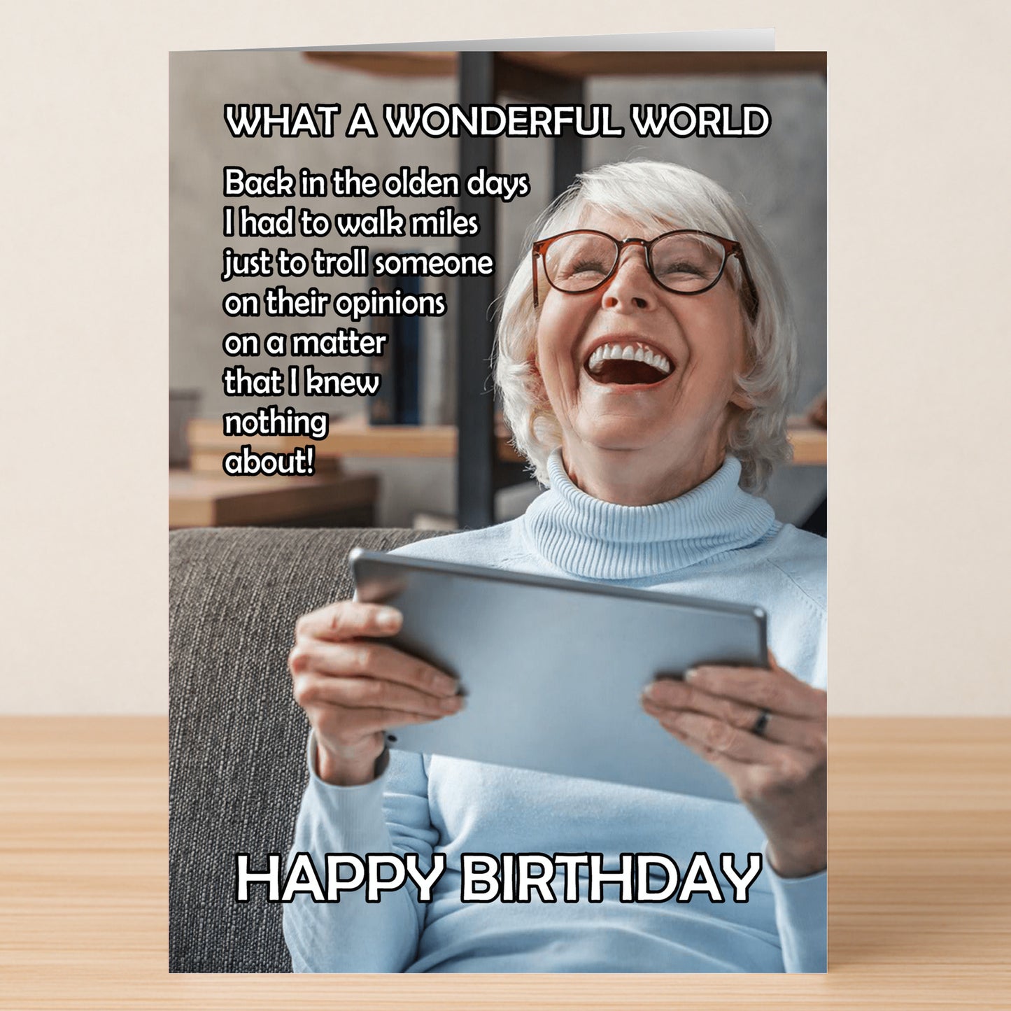 An older woman with gray hair and glasses sits on a couch, smiling as she holds a tablet—featured on Twisted Gifts' Wonderful World – Funny Birthday Card, perfect for anyone who loves humorous takes on sharing opinions!.