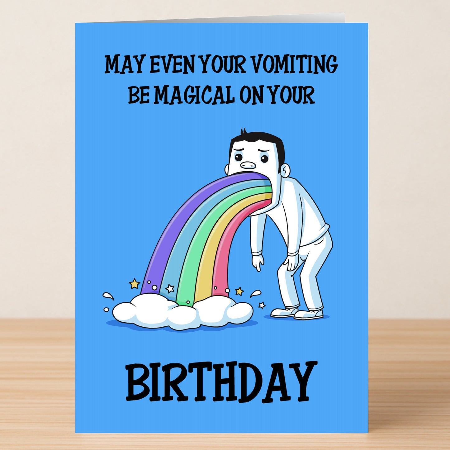The Magical Funny Birthday Card by Twisted Gifts features a cartoon vomiting a rainbow and stars onto a cloud, with the message "May even your vomiting be magical on your birthday." A fun pick for those who love humor and whimsy!.