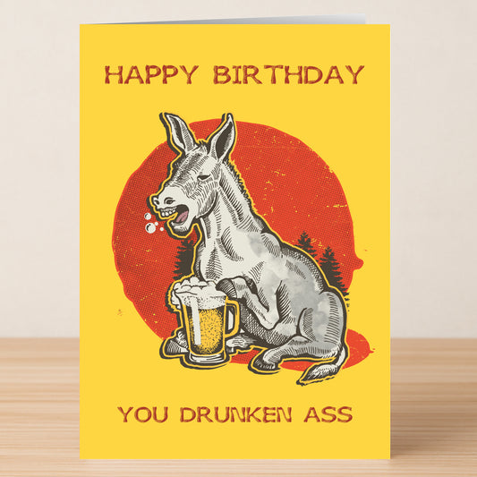 The Drunken Ass – Funny Birthday Card from Twisted Gifts features a donkey holding a beer and the message "HAPPY BIRTHDAY YOU DRUNKEN ASS" on a bright yellow background.