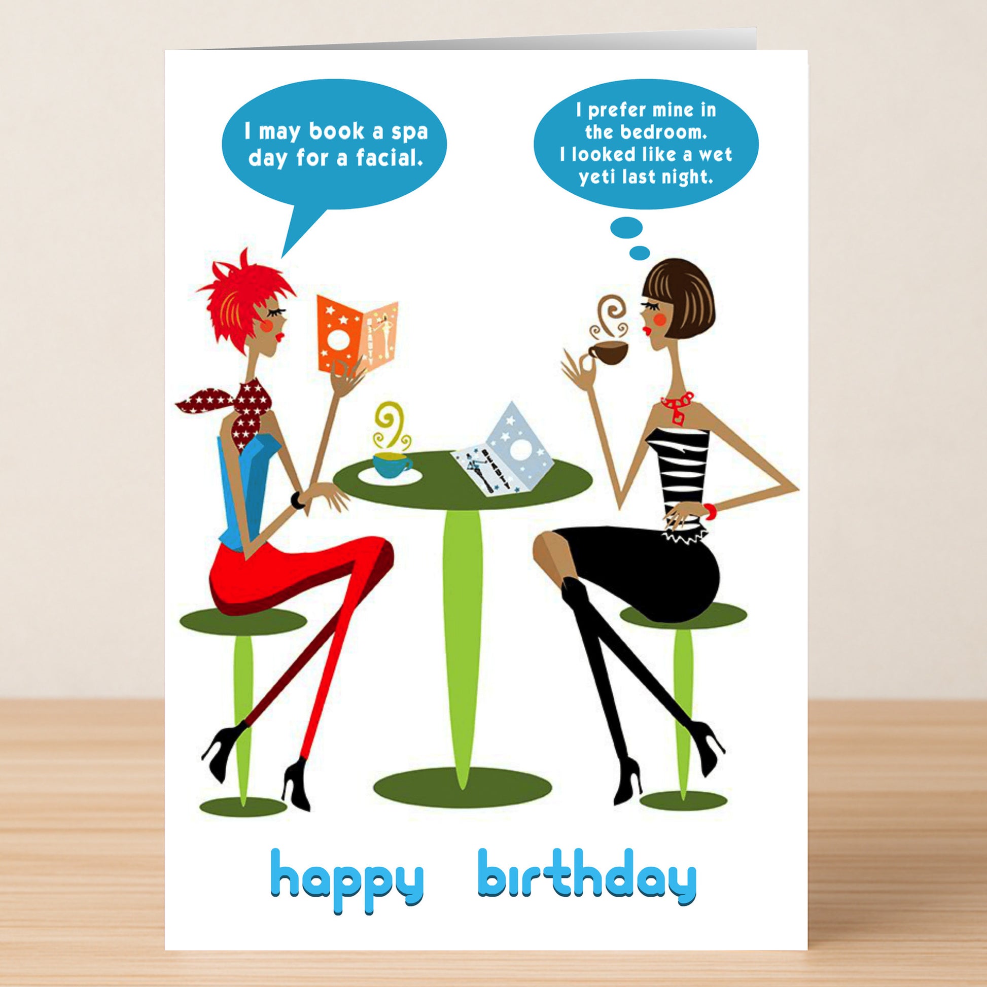 Two women sit at a small table, chatting over coffee. The Yeti – Rude Birthday Card by Twisted Gifts features speech bubble jokes about spa days and bedtime routines, with "happy birthday" text at the bottom.